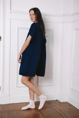 Camisa larga de manga corta, color gris claro, con cuello y botones negros. Presenta un pequeño bordado de corazón negro en el pecho.