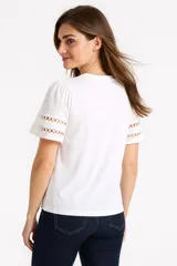 Remera verde oliva de algodón, con cuello redondo, mangas cortas abullonadas con detalle de calado y corte holgado.