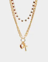 Set de dos collares dorados con cadenas de diferentes diseños. Uno con strass rojos y otro con dijes de corazón, perla y cruz.