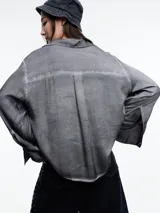 Camisa gris de manga larga confeccionada en viscosa teñida en frío, con efecto gastado. De corte relajado, con bolsillo delantero y puños amplios.