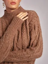 Sweater de cuello alto color beige con diseño de ochos en tejido grueso.