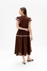 Vestido midi amarillo de lino, con volados en las mangas y detalle de volados y botones a lo largo del frente. Presenta un corte con talle marcado y falda escalonada.