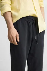 Pantalón largo verde oscuro de algodón con textura, corte recto y cintura elástica ajustable con cordón.