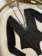 Body negro de lycra y encaje, con mangas largas de tul y cuello halter desmontable.