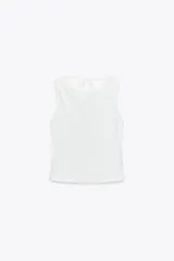 Top blanco de cuello redondo y tirantes anchos. Detalle de escote en espalda con tira cruzada ajustable con lazada.