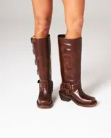 Botas de cuero vacuno color marrón con apliques de herrajes metálicos y plantilla entera para mayor confort. Taco de 6 cm.