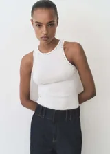 Musculosa blanca de algodón con cuello redondo y detalle de tachuelas plateadas en el cuello y las sisas. Diseño ajustado al cuerpo.