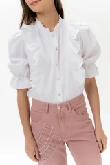 Blusa de lino color rojo con volados frontales que enmarcan el pecho, cuello redondo con mini volado y mangas 3/4 abullonadas con puño elástico. Presenta un cierre frontal con botones y una silueta relajada.