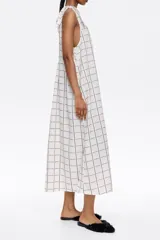 Vestido midi negro con estampado a cuadros blancos, corte recto, escote redondo y tirantes con lazos.