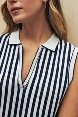 Chaleco tejido de punto sin mangas con rayas verticales azul marino y blancas, cuello polo blanco y corte ajustado.