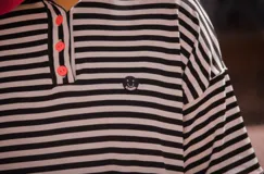 Remerón oversize unisex a rayas horizontales blancas y negras, con cuello tejido en color rosa chicle.