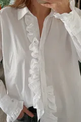Camisa blanca de manga larga con volados en el frente y en los puños.