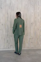 Pantalón verde con finas rayas verticales blancas, corte recto, tiro alto y bolsillos laterales.