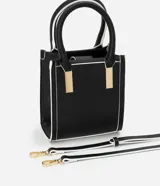 Bolso transversal pequeño tipo bandolera, color negro con detalles en blanco y herrajes dorados. Tiene correa de mano, asa larga desmontable y cierre superior.
