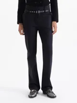 Pantalón sastrero negro con raya marcada al centro y pierna recta. Incluye un cinturón desmontable de cuero vacuno con herrajes metálicos. Tiene bolsillos delanteros biselados y un bolsillo ojal en la espalda.