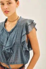 Camisa color crema de corte corto con escote redondo, mangas cortas con volados y jareta ajustable en el ruedo.