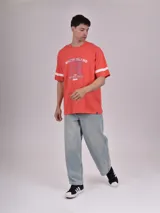 Remera manga corta color gris con estampado frontal de texto 'BRKLN COLLEGE' y dos franjas negras en las mangas.