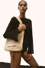Bolso tipo tote de paja trenzada color beige con asas dobles y la inscripción "Amour Paris" en negro.