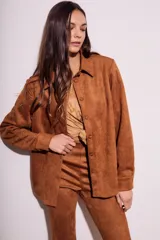 Camisa color marrón de gamuza sintética, con cuello clásico, cierre frontal con botones y mangas largas con puños abotonados.