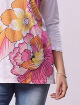 Blusa blanca de algodón con estampado de flores en tonos naranja y rosa, escote redondo con puntilla y mangas 3/4.