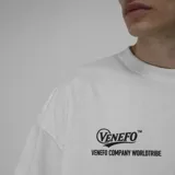 Remera blanca de algodón, corte oversize y manga corta, con estampado trasero en negro que incluye el logo "VENEFO TM", "Industries Company", "004@1994" y "WORLDTRIBE CO".