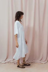 Vestido midi color beige de lino, corte amplio, escote en V y mangas cortas. Tiene dos volados en la falda.