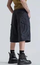 Pantalón negro con corte ancho, bolsillos laterales con solapa y detalle de cierre a la altura de la rodilla para convertirlo en short.