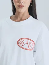 Remera blanca de corte holgado con estampado de dragones en círculo con texto 'No Art Uruguay' y 'Castillo de Piria'.