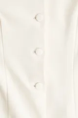 Blazer entallado color crema, de punto interlock pesado con cuello redondo y botones forrados hasta la cintura, creando un leve corte acampanado.