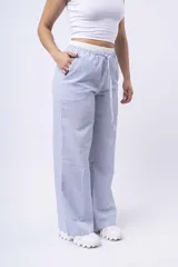 Pantalón de tela a rayas verticales celestes y blancas, con corte amplio, cintura elástica y cordón ajustable.