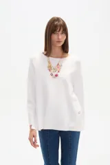 Sweater blanco liso, de corte holgado, con cuello a la base y broches decorativos en los laterales.