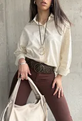 Camisa beige de manga larga con bordado floral en las mangas y cuello clásico.