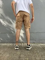Bermuda de gabardina color marrón claro, corte recto, con bolsillos cargo laterales y bolsillos traseros con solapa.