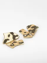 Par de aros colgantes dorados con forma geométrica irregular y textura martillada.