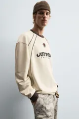 Sudadera color crema de corte relaxed fit, con cuello redondo y manga larga. Presenta un estampado en el frente con la palabra "ULTRAVEX" en letras negras y la palabra "FUTURIO" debajo.