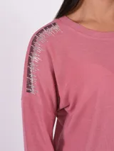 Blusa de tejido de punto color rosa viejo, con cuello redondo y mangas largas. Presenta apliques de strass en los hombros.