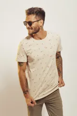 Remera de manga corta color beige claro con cuello redondo y estampado repetitivo de figuras pequeñas en tonos tierra y verde agua.