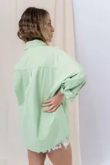 Camisa color crema de algodón liviano, calce oversize, con cuello camisero, cierre abotonado, mangas largas con opción de arremangado y dos bolsillos frontales con solapa.