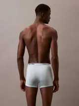 Pack de tres bóxer brief Calvin Klein, uno celeste liso, uno verde agua liso y uno gris con estampado del logo de la marca.