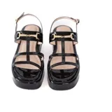 Sandalias negras de charol con plataforma de 5 cm, tiras frontales y pulsera ajustable al tobillo con detalle metálico dorado.