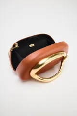 Bolso marrón con forma de caja, con cierre dorado en forma de C y asa de cadena dorada para usar como bandolera.