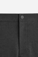 Pantalón negro de corte slim fit, confeccionado en tejido elástico. Cuenta con cintura elástica, bolsillos frontales y traseros de vivo. Cierre frontal con cremallera y botón.
