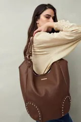 Bolso shopper negro de símil cuero texturizado con asas de hombro y detalles de tachas metálicas.