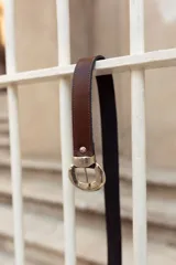 Cinturón negro de cuero gamuzado con hebilla plateada con diseño.