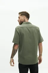 Camisa de manga corta color beige, con textura tipo crepé y cuello camisero.