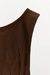 Mono corto marrón de punto, semitransparente, confeccionado en hilatura con poliamida. Escote recto y tirantes anchos.