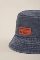 Gorro tipo bucket color lila con etiqueta naranja con el logo de la marca Benson & Thomas.