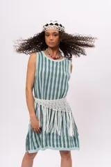 Vestido tejido a rayas verticales en tonos celeste y gris, sin mangas, con cuello redondo y corte recto. Incluye cinturón tejido con flecos.