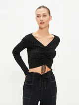 Buzo crop top negro de tejido de punto acanalado con escote en V y cordón ajustable en el centro.