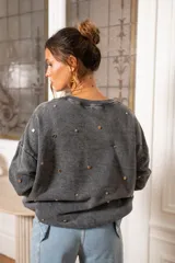 Sweater blanco de algodón con cuello redondo y mangas largas. Decorado con tachas plateadas en el frente y las mangas.